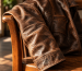 Brown leather jacket sleeve with natural creasing and patina draped over a wooden chair